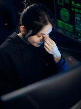 A woman collecting her thoughts in front of a computer